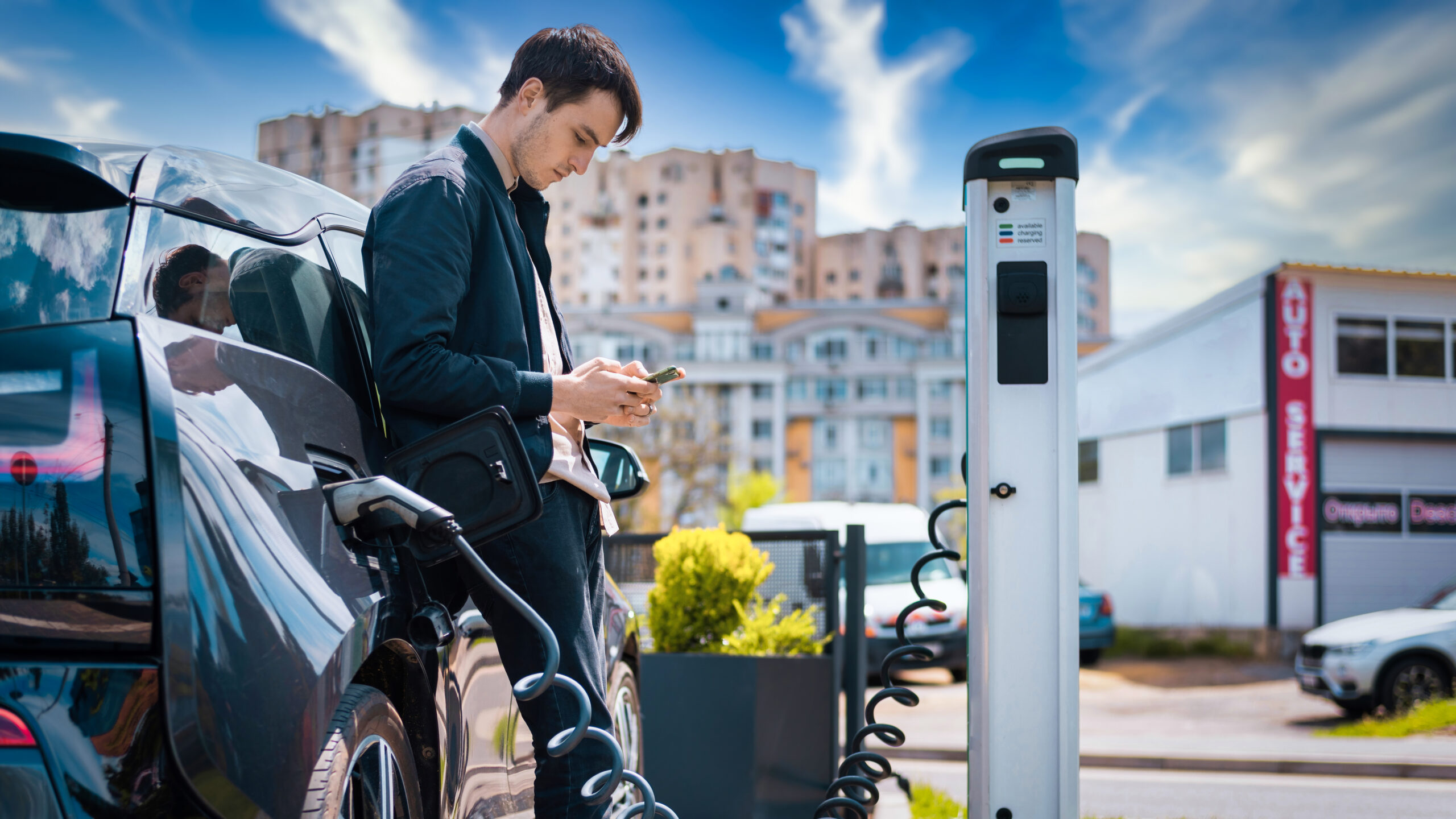 Mężczyzna ładujący swój samochód elektryczny.