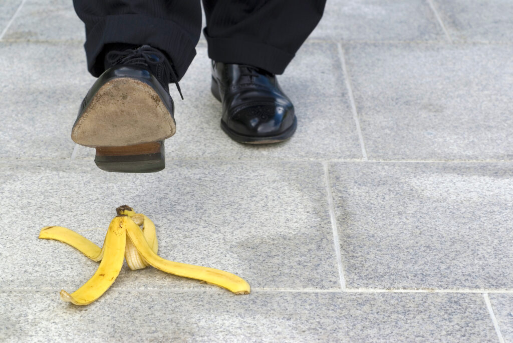idący mężczyzna w garniturze robi krok tuż nad skórką od banana.